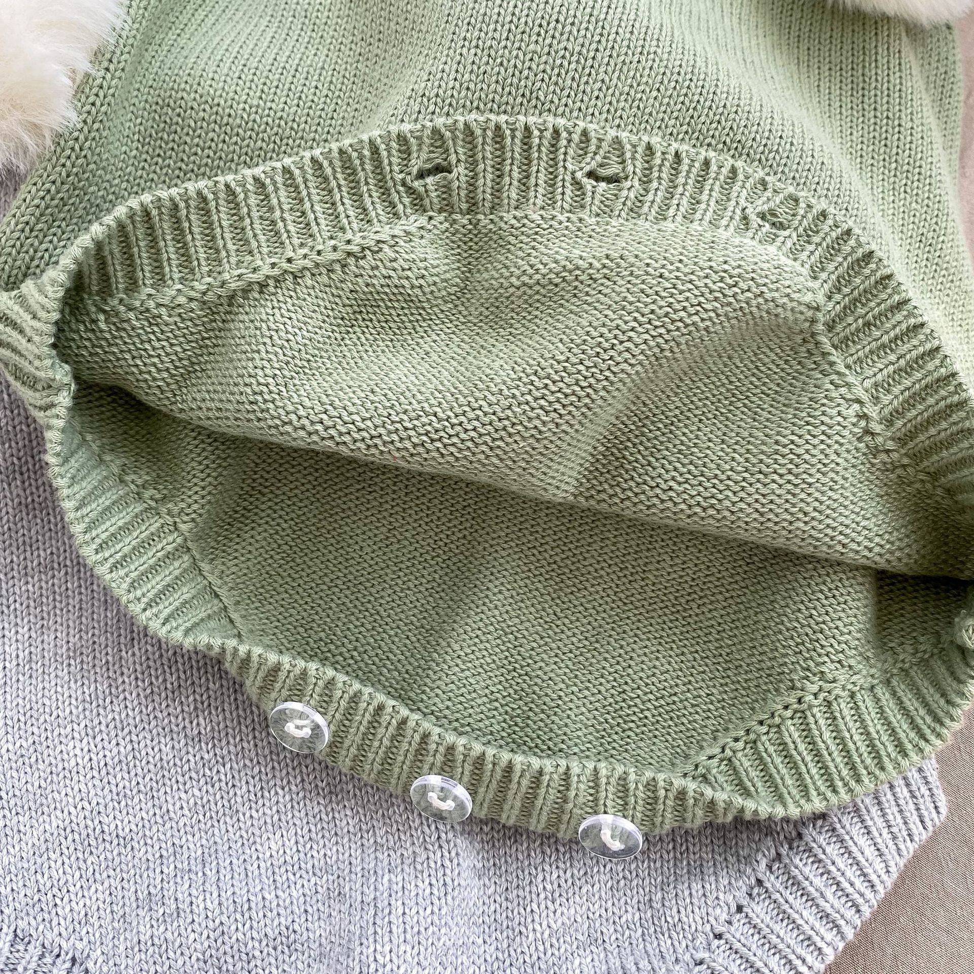 Baby girl wearing a plush ball camisole knitted vest in green, showcasing its soft cotton material and stylish design.