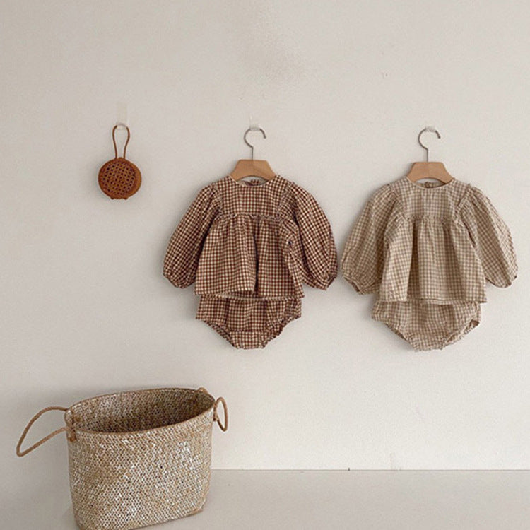 A stylish 3-piece baby girl outfit featuring a plaid pattern blouse, matching shorts, and a headband in apricot and brown colors.