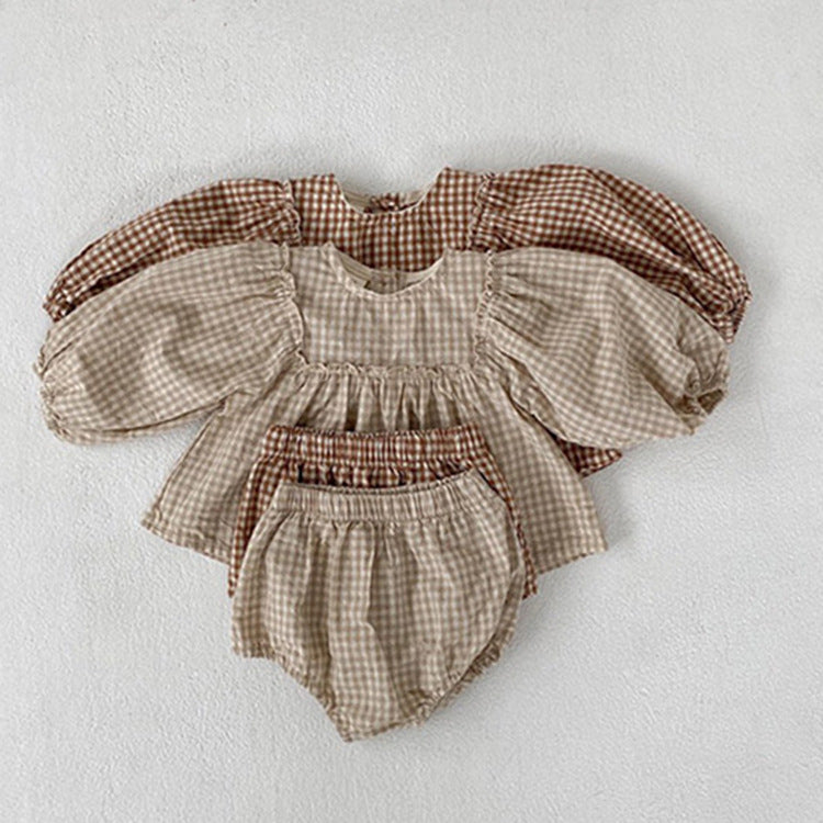 A stylish 3-piece baby girl outfit featuring a plaid pattern blouse, matching shorts, and a headband in apricot and brown colors.