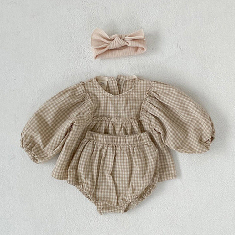 A stylish 3-piece baby girl outfit featuring a plaid pattern blouse, matching shorts, and a headband in apricot and brown colors.