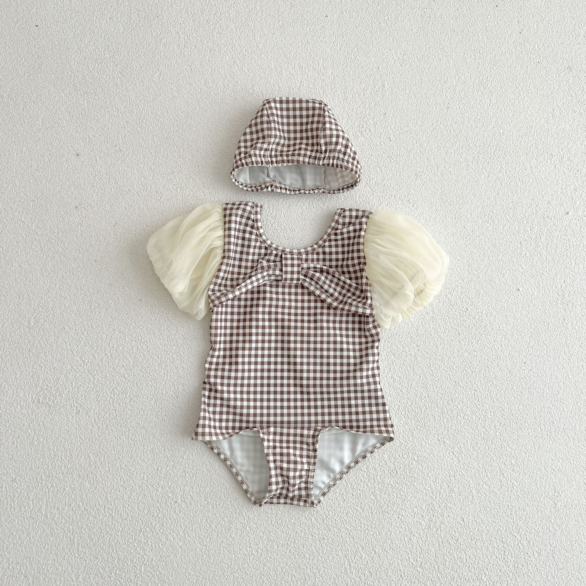 Baby girl swimwear featuring plaid pattern and mesh sleeves, complete with a matching sun hat.