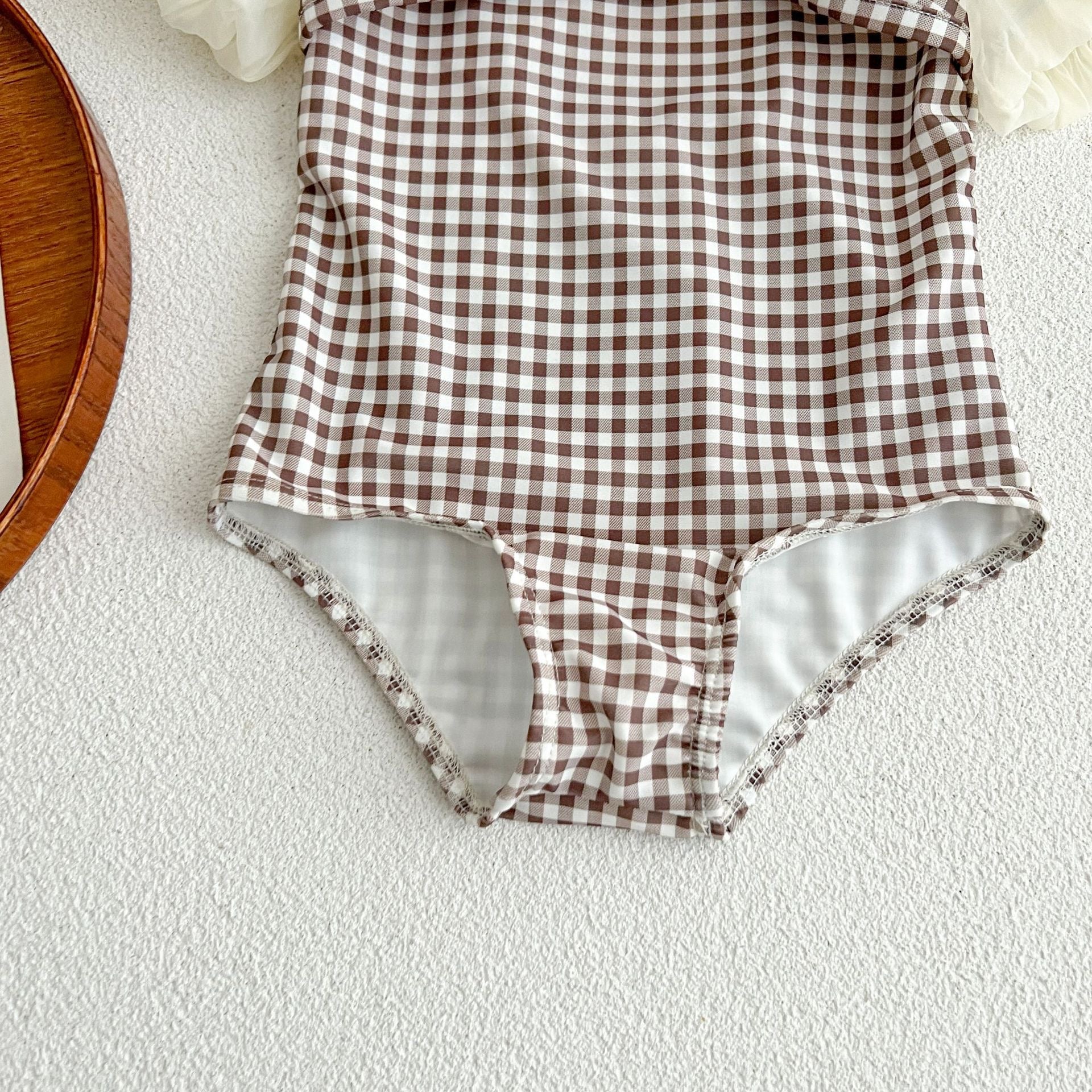 Baby girl swimwear featuring plaid pattern and mesh sleeves, complete with a matching sun hat.