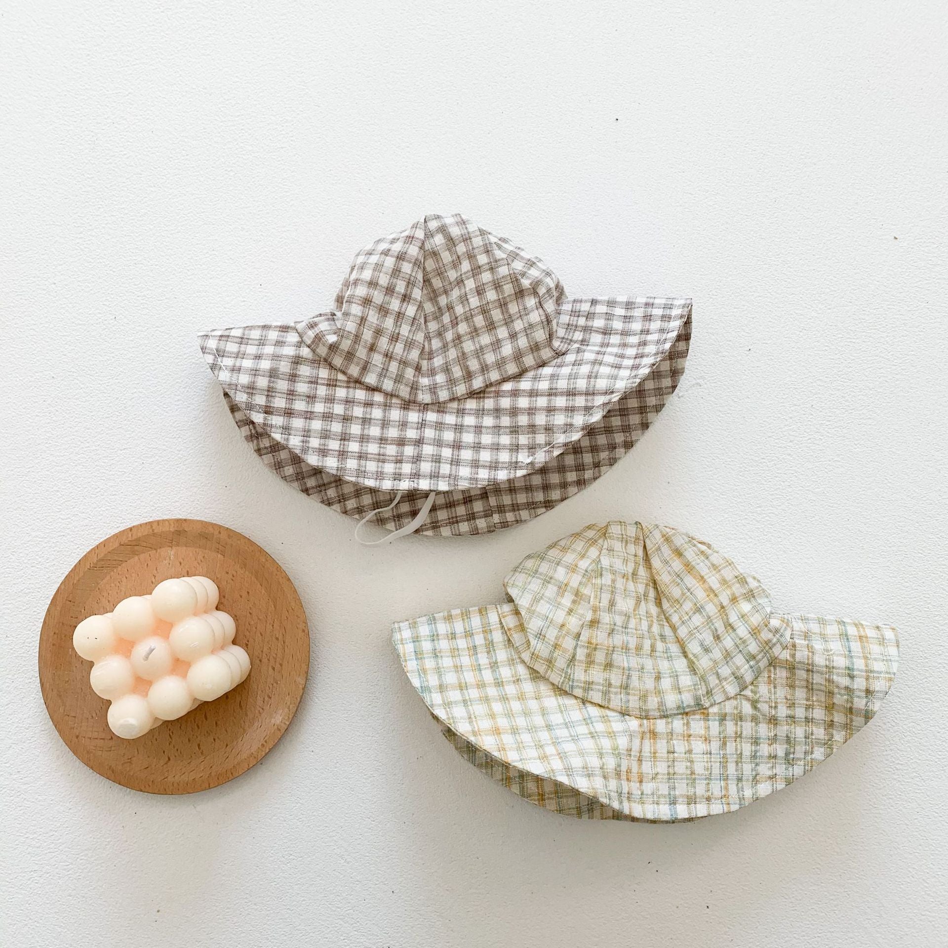 Baby girl wearing a stylish plaid pattern outfit with short sleeves, backpack pants, and a matching hat, perfect for summer.