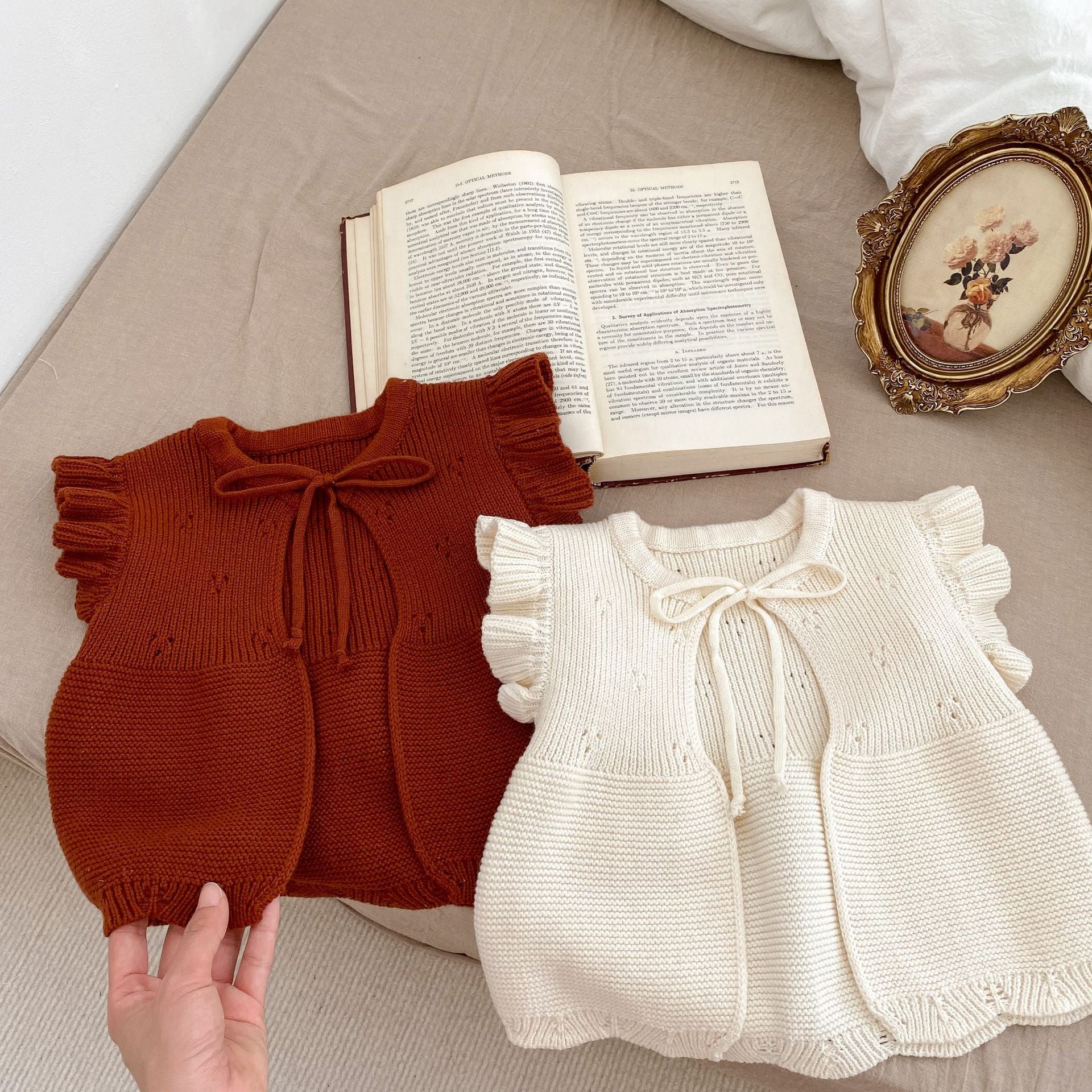 Baby girl wearing a solid color cardigan with butterfly sleeves, showcasing a cute and stylish design.