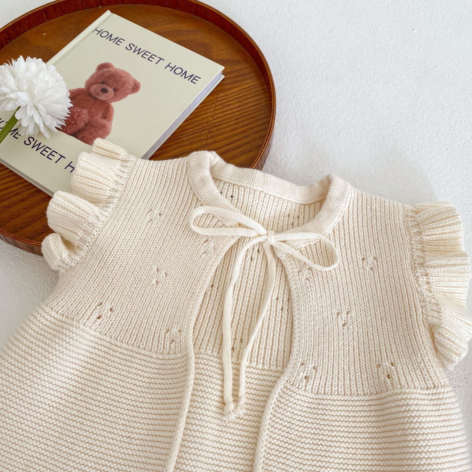 Baby girl wearing a solid color cardigan with butterfly sleeves, showcasing a cute and stylish design.