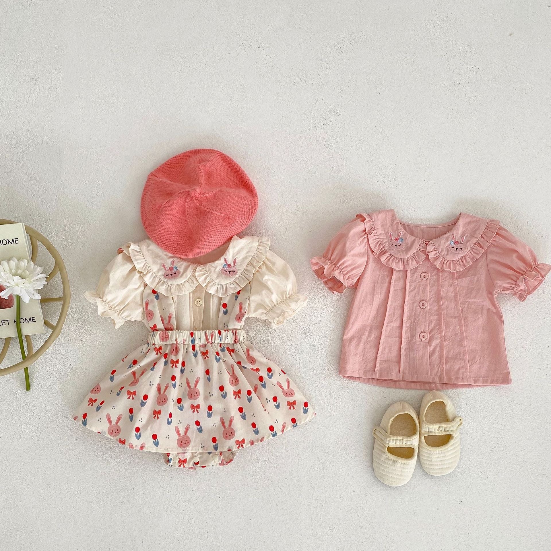 Baby girl wearing a solid color doll neck blouse with a strap dress, showcasing soft cotton fabric in pink and floral patterns.