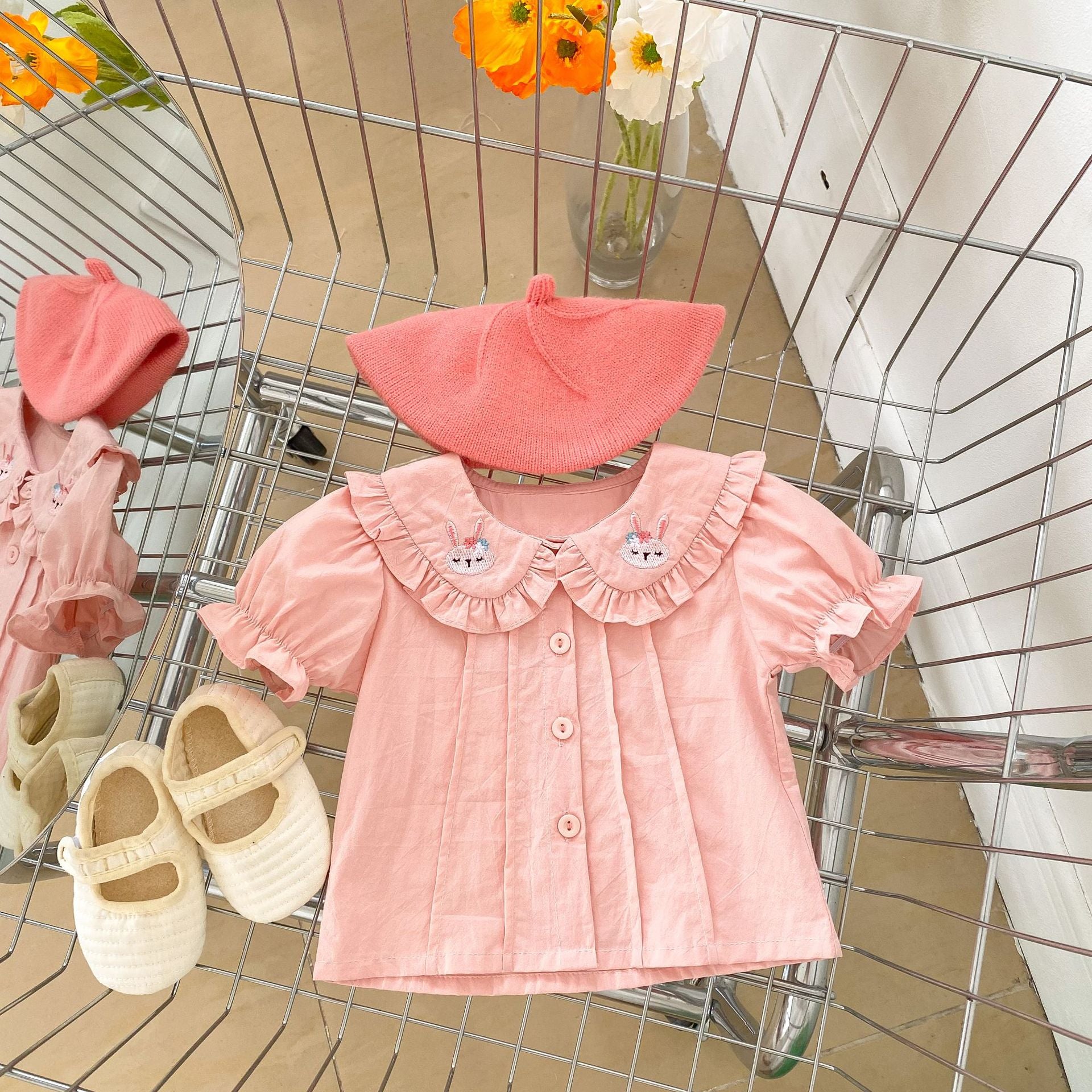 Baby girl wearing a solid color doll neck blouse with a strap dress, showcasing soft cotton fabric in pink and floral patterns.