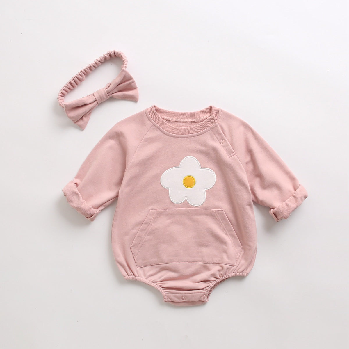 Baby girl onesie in pink with floral embroidery and pocket, made from soft cotton fabric.