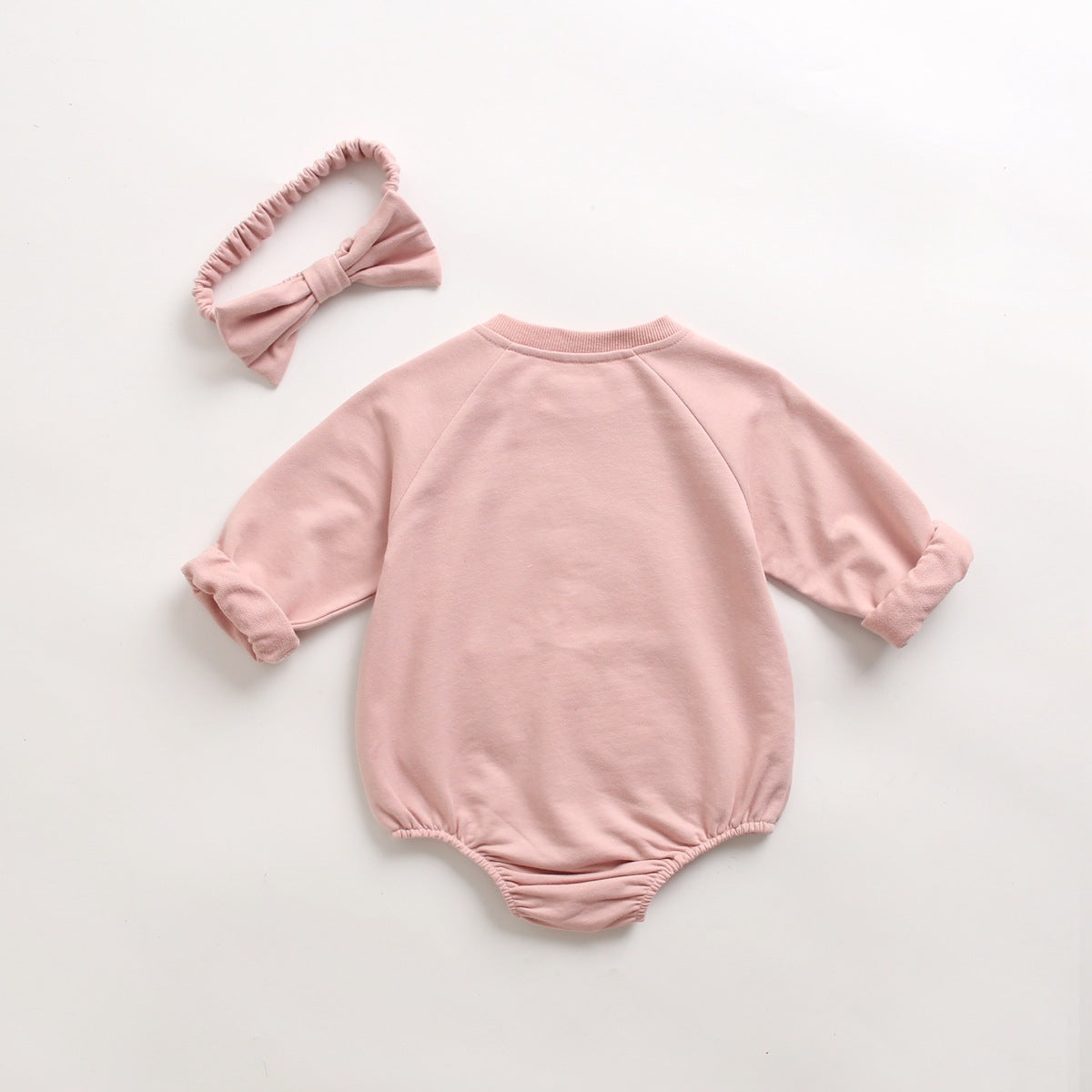 Baby girl onesie in pink with floral embroidery and pocket, made from soft cotton fabric.