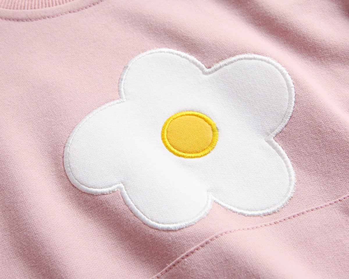 Baby girl onesie in pink with floral embroidery and pocket, made from soft cotton fabric.