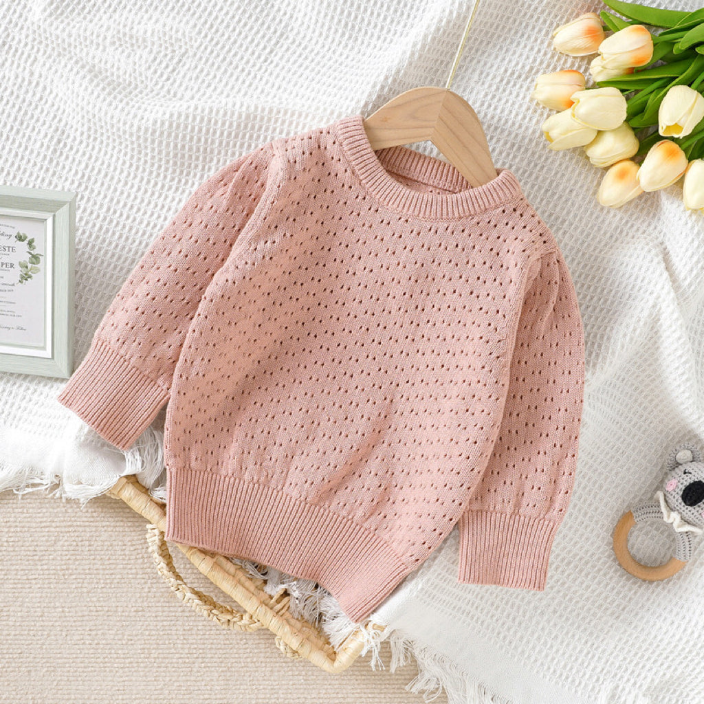 Baby girl wearing a solid color hollow carved design cotton sweater in pink, showcasing its stylish and cozy features.