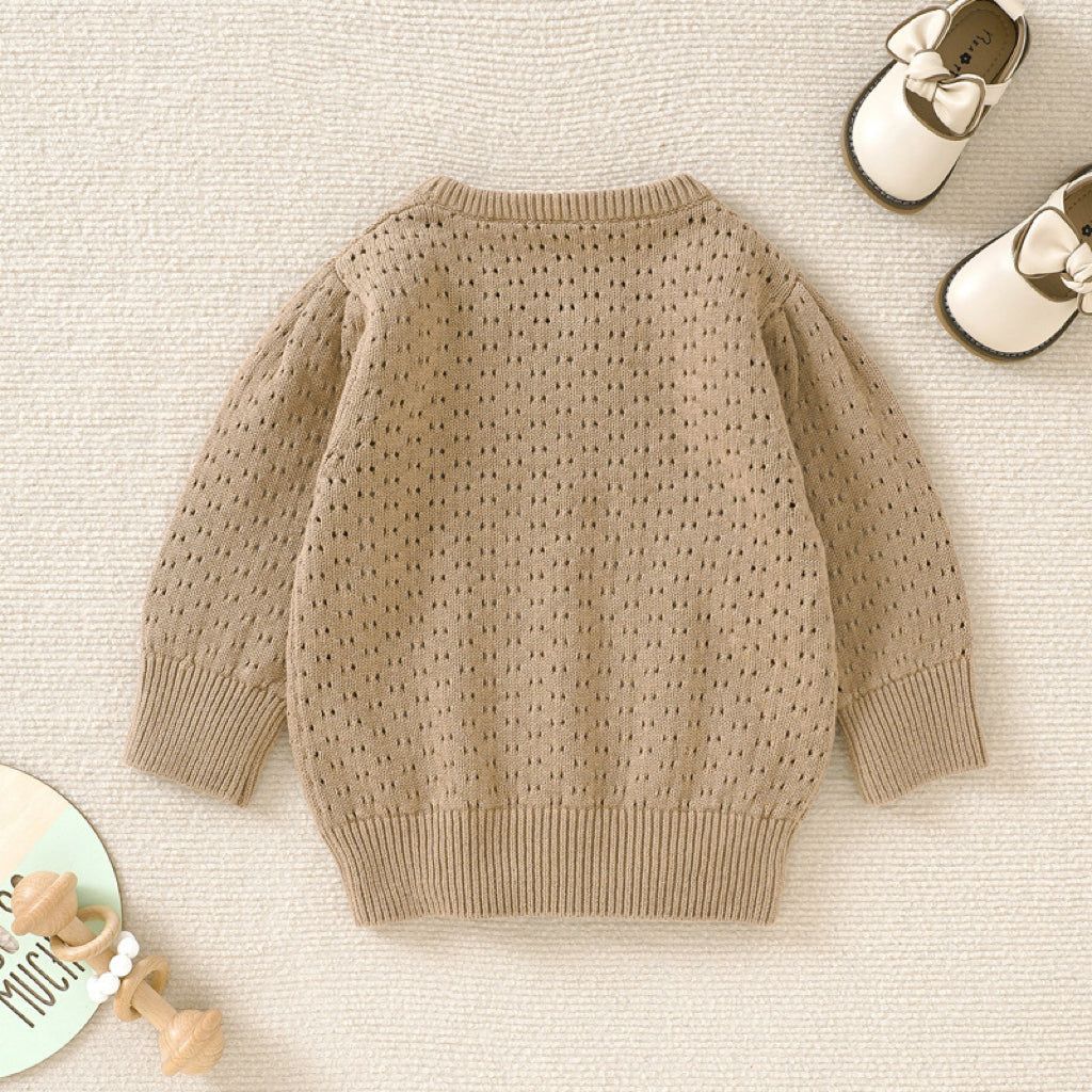 Baby girl wearing a solid color hollow carved design cotton sweater in pink, showcasing its stylish and cozy features.