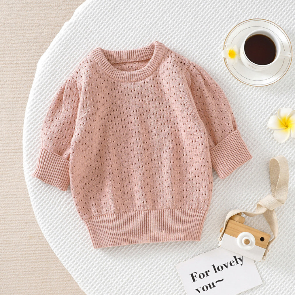 Baby girl wearing a solid color hollow carved design cotton sweater in pink, showcasing its stylish and cozy features.