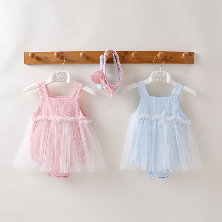 A baby girl wearing a solid color mesh patchwork sleeveless dress in pink, complemented by a delicate headband.