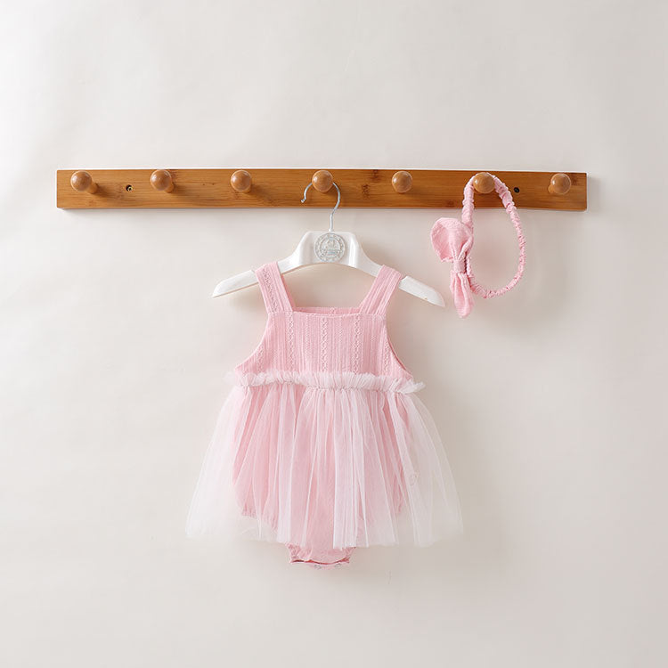 A baby girl wearing a solid color mesh patchwork sleeveless dress in pink, complemented by a delicate headband.