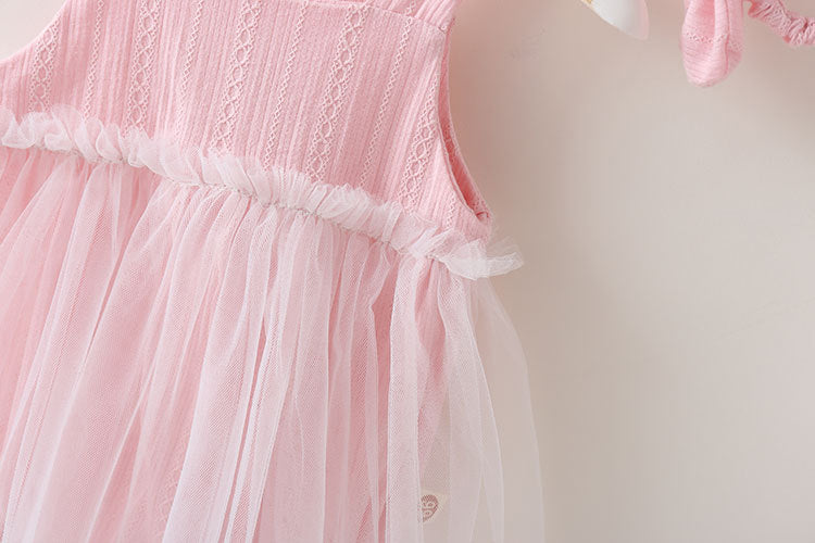 A baby girl wearing a solid color mesh patchwork sleeveless dress in pink, complemented by a delicate headband.