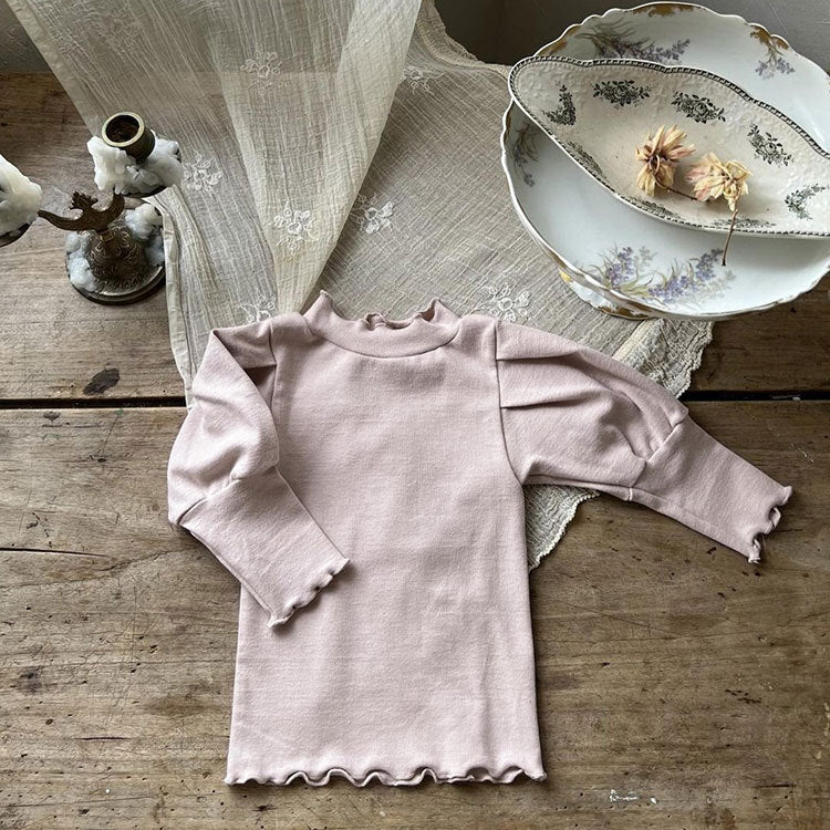 Baby girl wearing a solid color trim design long puff sleeves cotton shirt in pink, showcasing its stylish and comfortable design.