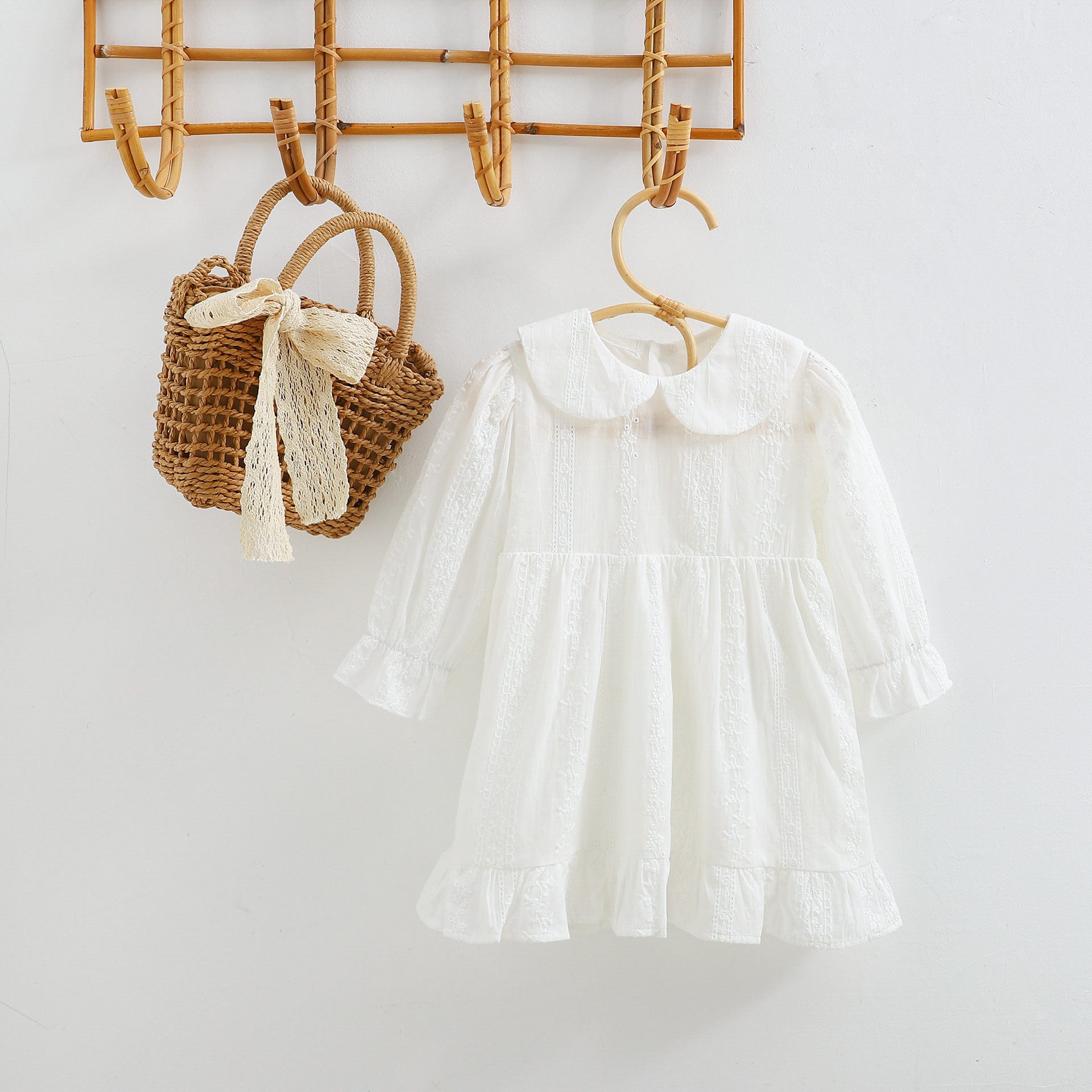 A beautiful baby girl dress made of white mesh fabric featuring an elegant embroidered pattern and long sleeves, perfect for special occasions.