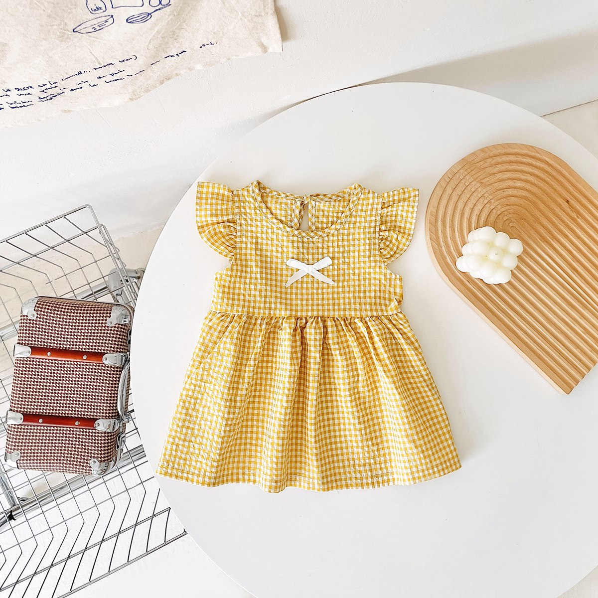 A variety of baby girl summer dresses in floral and plaid patterns, showcasing vibrant colors like pink, blue, and yellow.