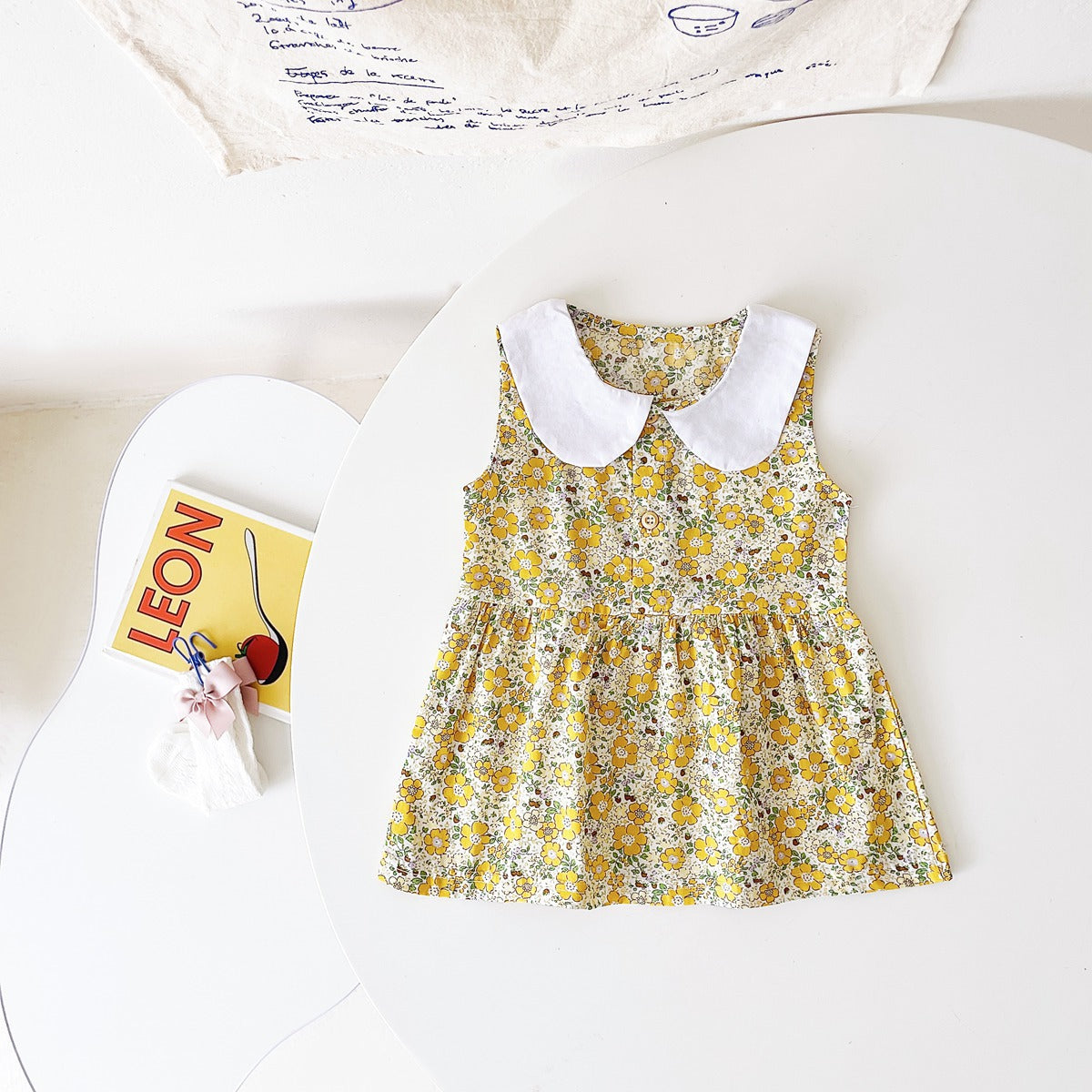 A variety of baby girl summer dresses in floral and plaid patterns, showcasing vibrant colors like pink, blue, and yellow.