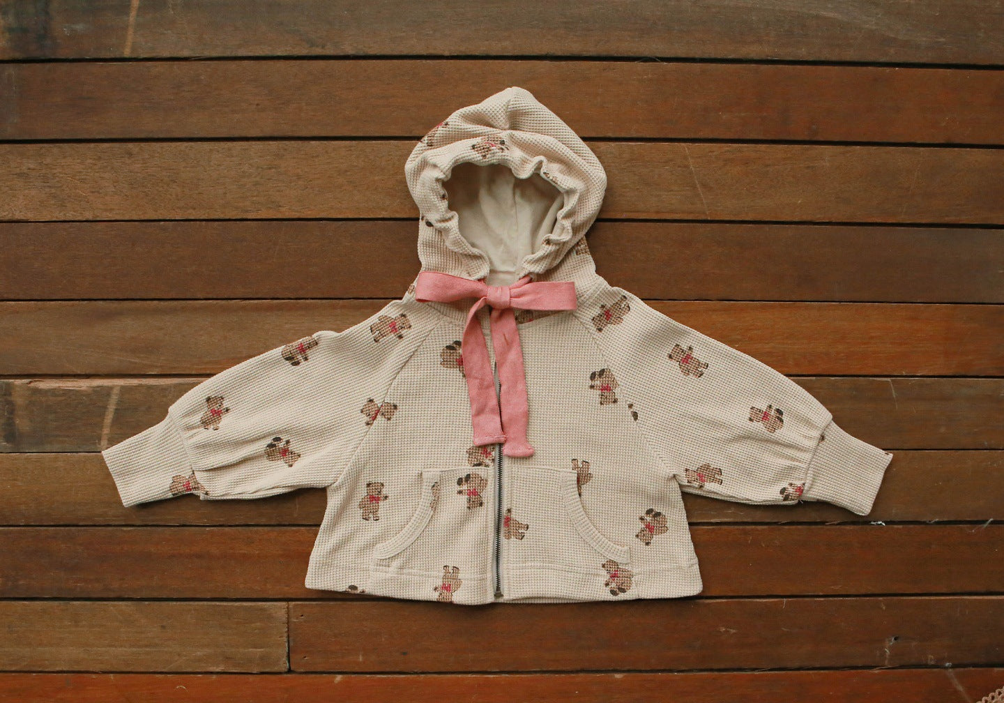 Baby girl wearing a cozy bear pattern waffle knit jacket coat with a hood, showcasing khaki color and zipper design.