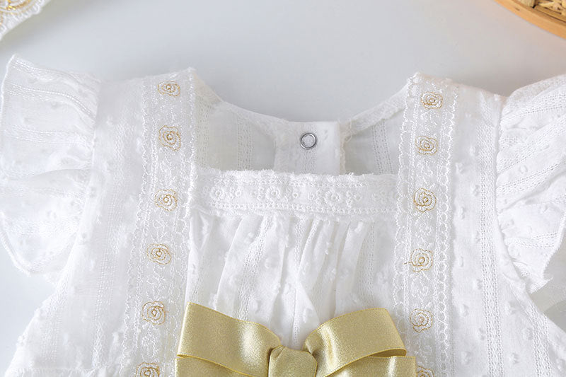 Baby girl wearing a solid white onesie with a gold bow tie patch, perfect for summer outings.