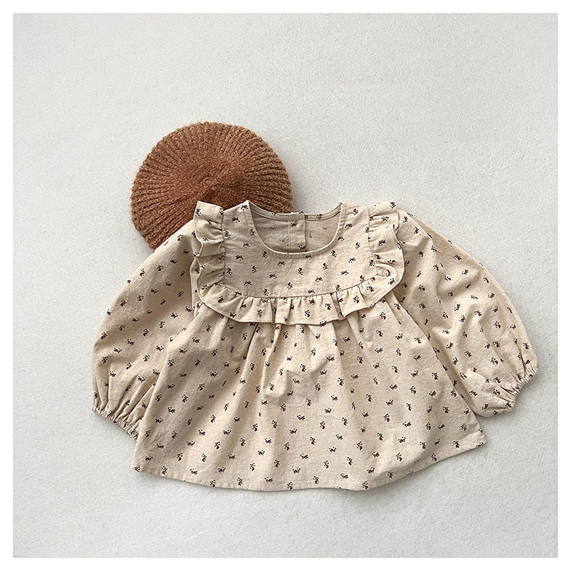 Baby girl wearing a floral print crew neck long sleeve top in apricot color, showcasing countryside style.