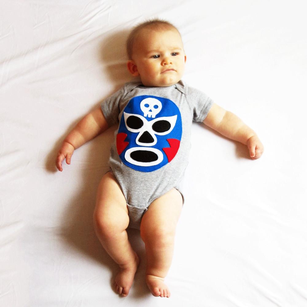 A vibrant blue baby onesie featuring a colorful Luchador Azul design, showcasing a playful Mexican wrestler character, perfect for infants.