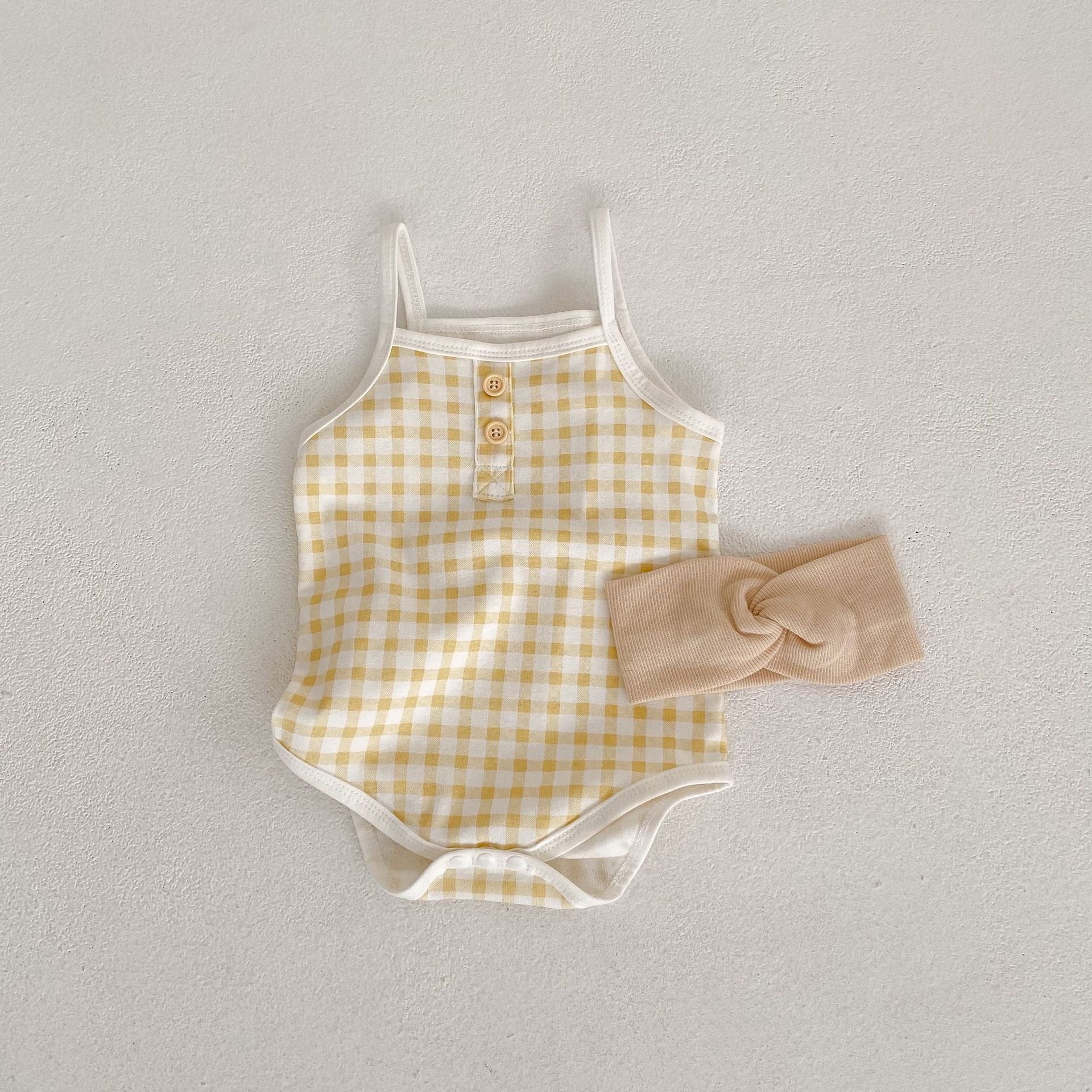 Baby girl wearing a stylish plaid pattern sling colorblock summer onesie in vibrant colors.