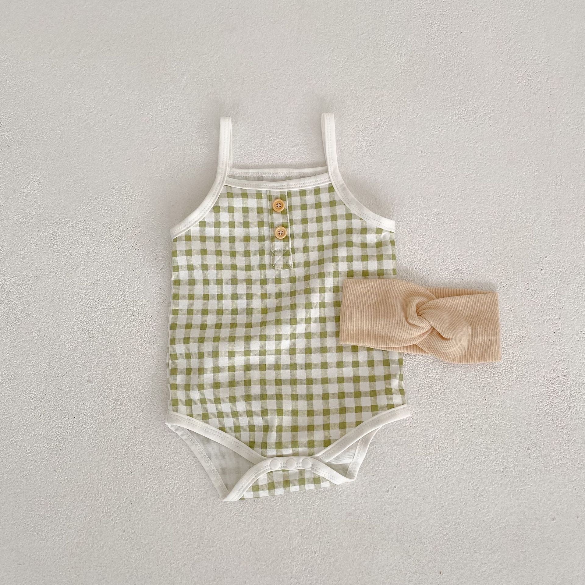 Baby girl wearing a stylish plaid pattern sling colorblock summer onesie in vibrant colors.