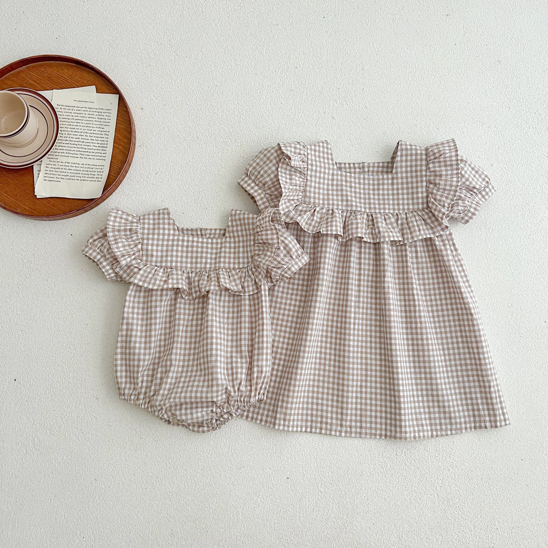 Baby girl wearing a plaid pattern square neck puff sleeves onesie and dress in blue, showcasing a stylish summer outfit.