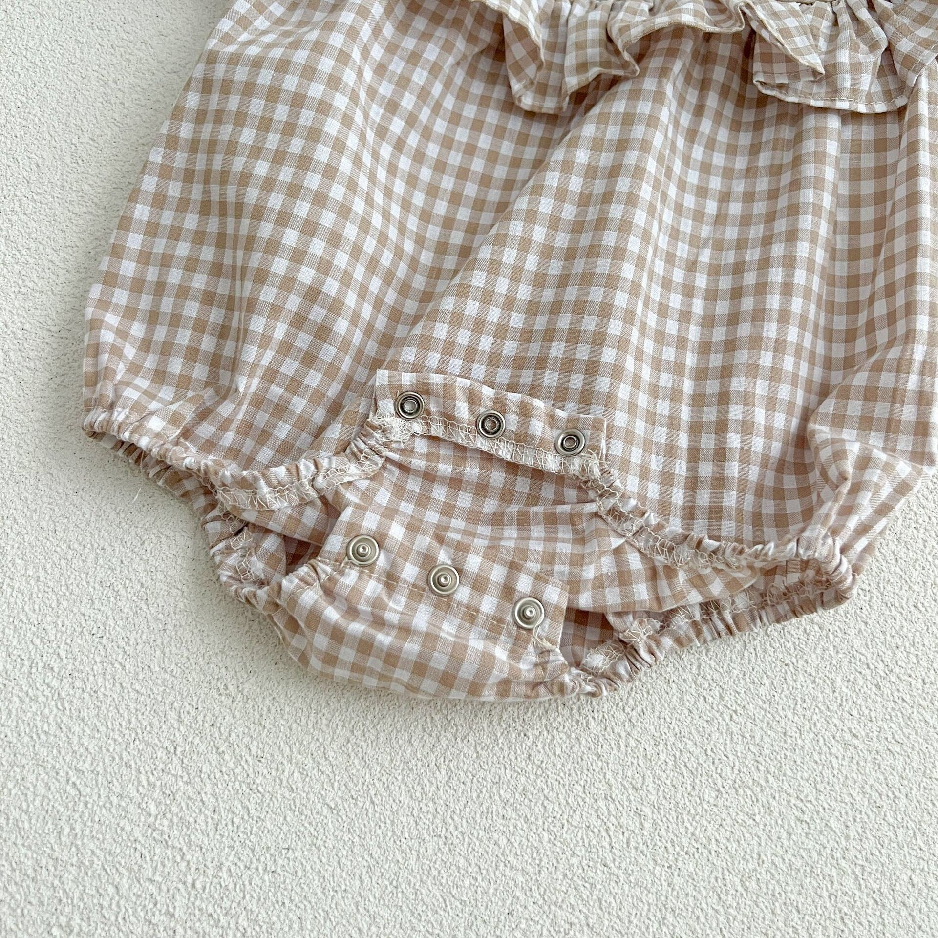 Baby girl wearing a plaid pattern square neck puff sleeves onesie and dress in blue, showcasing a stylish summer outfit.