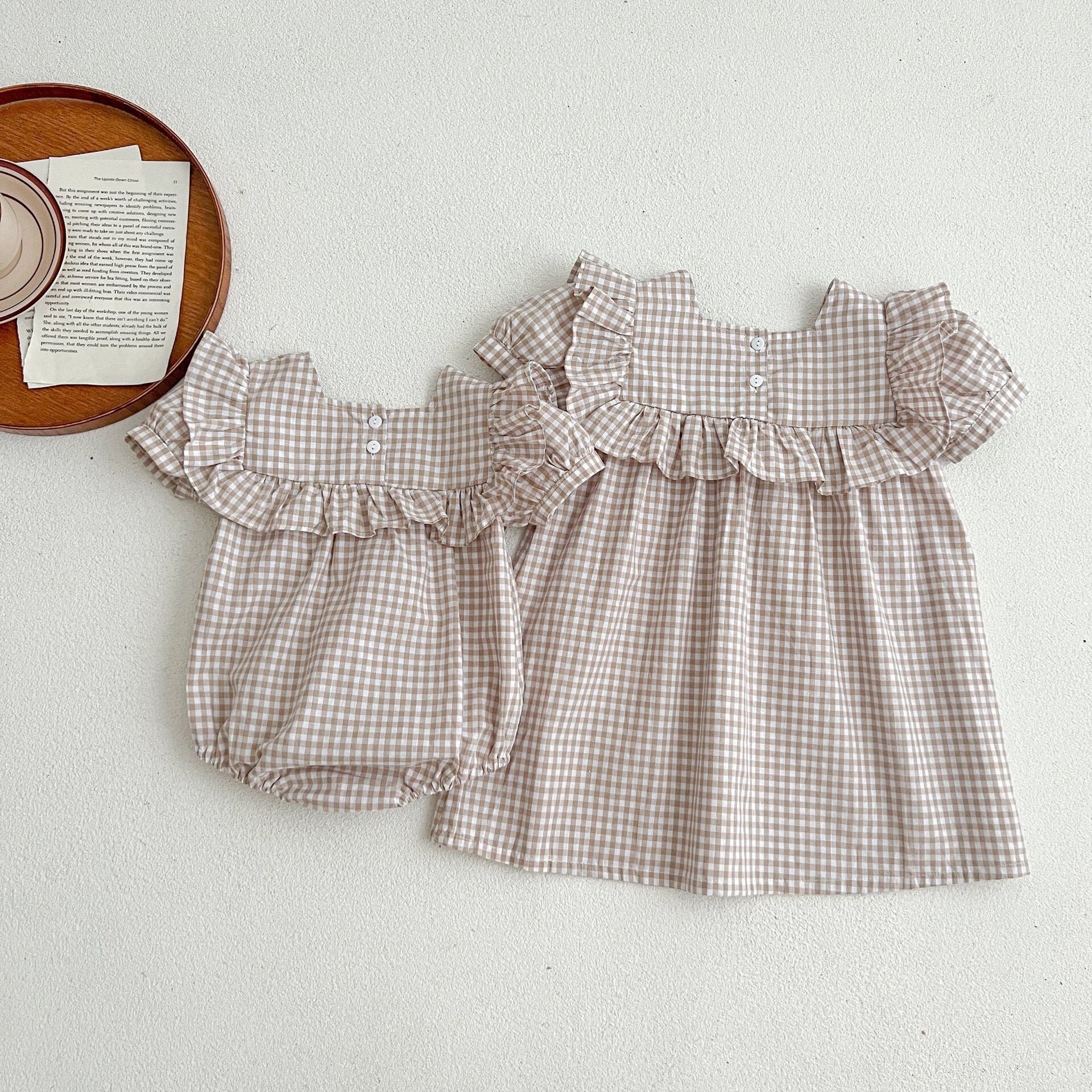 Baby girl wearing a plaid pattern square neck puff sleeves onesie and dress in blue, showcasing a stylish summer outfit.