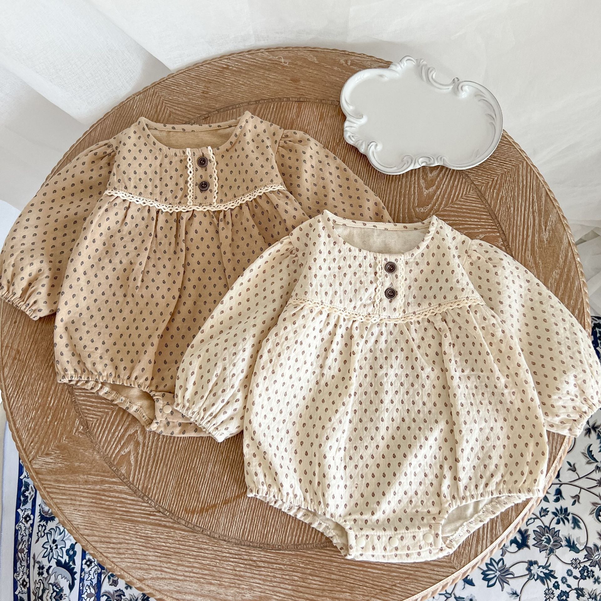 Baby girl wearing a polka dot pattern long sleeve lace design onesie in apricot color, showcasing its stylish and comfortable design.