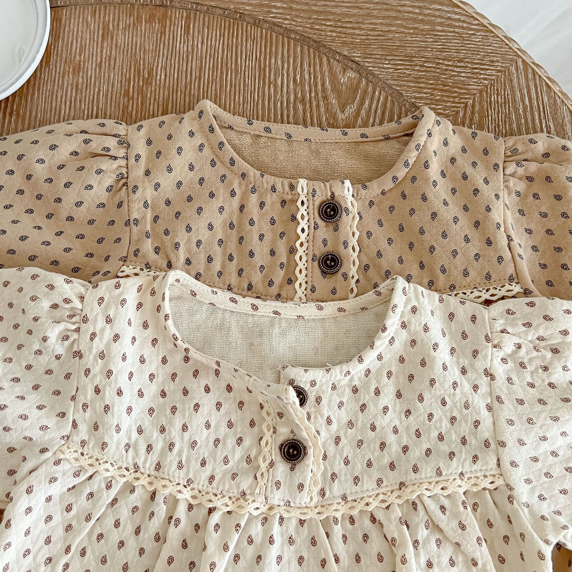 Baby girl wearing a polka dot pattern long sleeve lace design onesie in apricot color, showcasing its stylish and comfortable design.