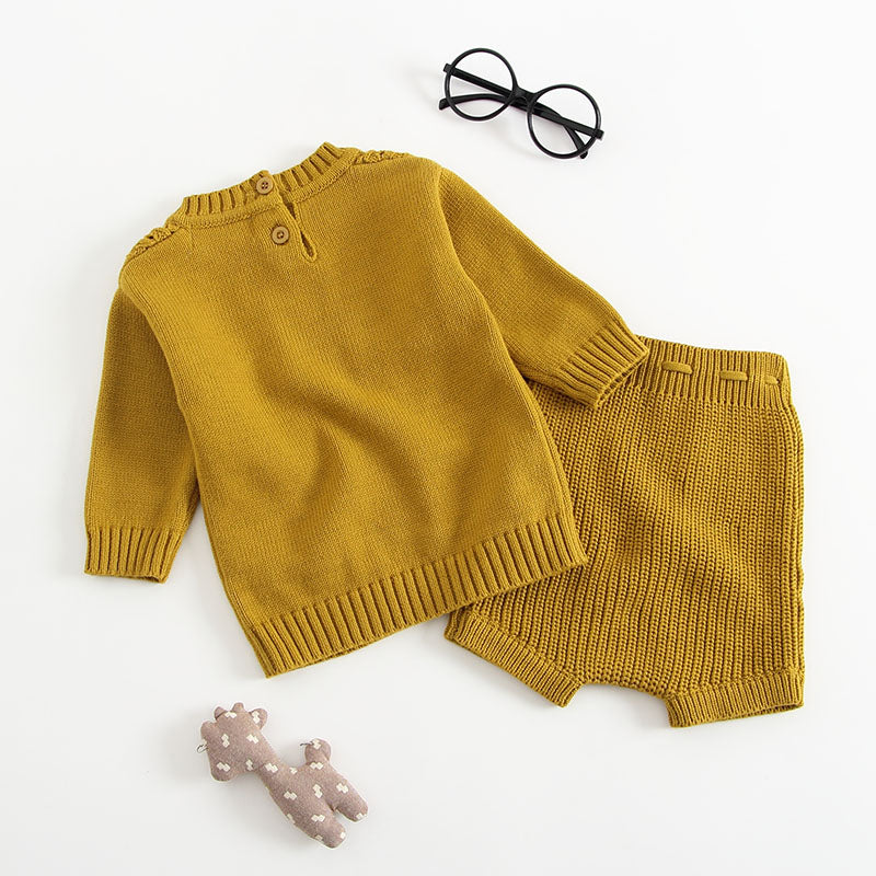 Baby girl wearing a solid color hollow carved knitwear set in white and yellow, showcasing a charming design.