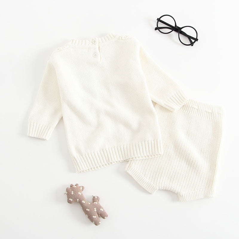 Baby girl wearing a solid color hollow carved knitwear set in white and yellow, showcasing a charming design.