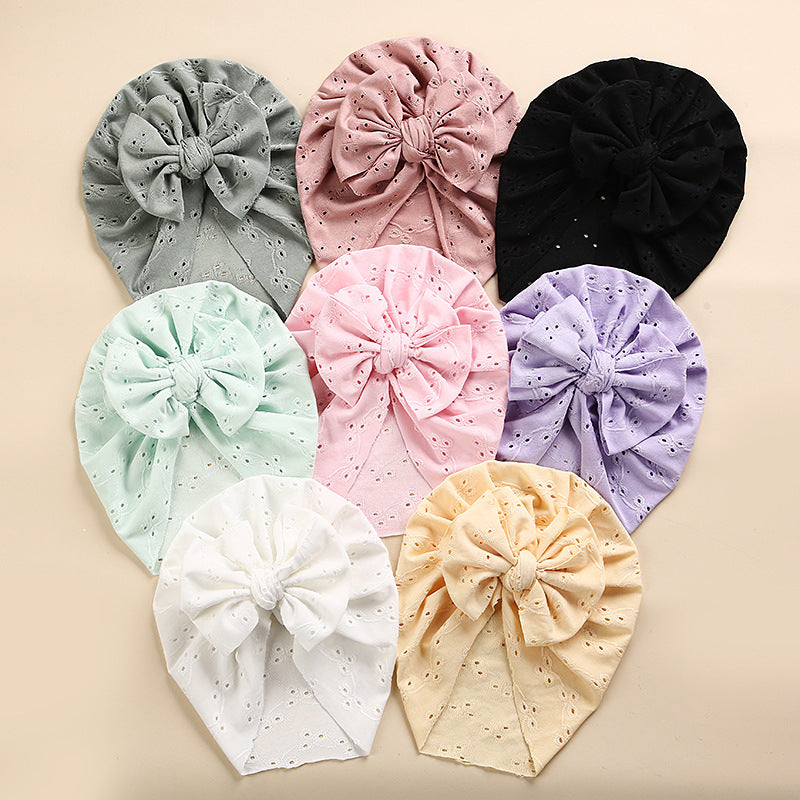 A collection of soft cotton baby caps in various colors with lace trim, perfect for keeping babies cool and stylish.