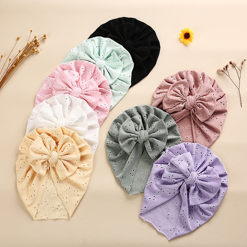 A collection of soft cotton baby caps in various colors with lace trim, perfect for keeping babies cool and stylish.