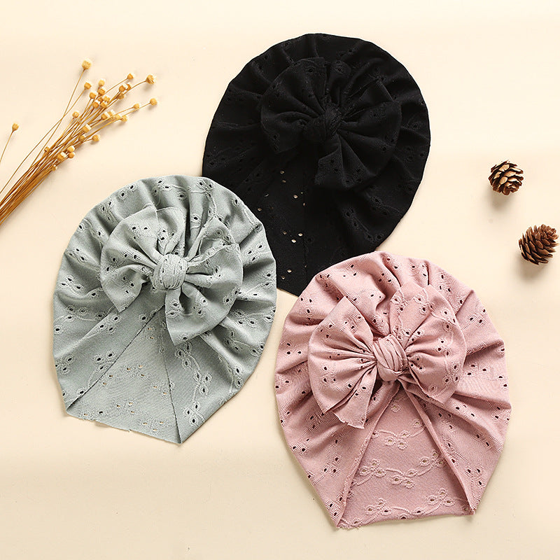 A collection of soft cotton baby caps in various colors with lace trim, perfect for keeping babies cool and stylish.