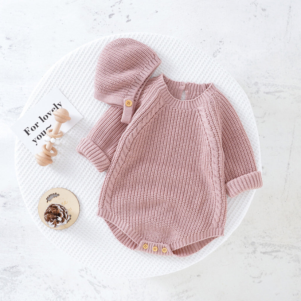 A cozy baby wearing a solid color long sleeve knitted woolen onesie in pink, showcasing its ribbed trim and snap-button closure.