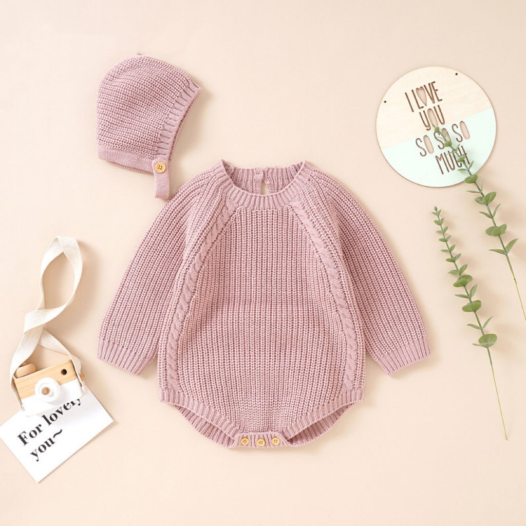 A cozy baby wearing a solid color long sleeve knitted woolen onesie in pink, showcasing its ribbed trim and snap-button closure.