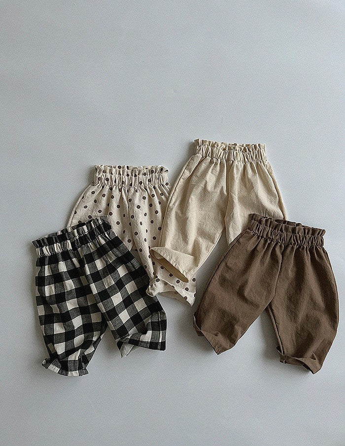 A pair of Baby Solid Color Loose Casual Pants in various colors including black, beige, apricot, and brown, made from soft cotton fabric.