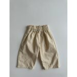 A pair of Baby Solid Color Loose Casual Pants in various colors including black, beige, apricot, and brown, made from soft cotton fabric.