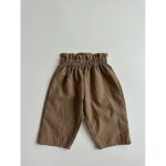 A pair of Baby Solid Color Loose Casual Pants in various colors including black, beige, apricot, and brown, made from soft cotton fabric.