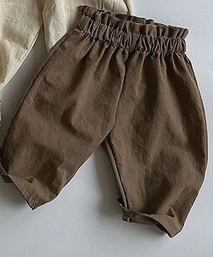 A pair of Baby Solid Color Loose Casual Pants in various colors including black, beige, apricot, and brown, made from soft cotton fabric.