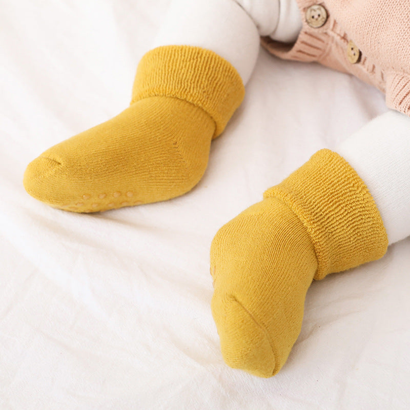 A pair of baby thickened soft cotton anti-slip floor socks in solid color, designed for comfort and safety.