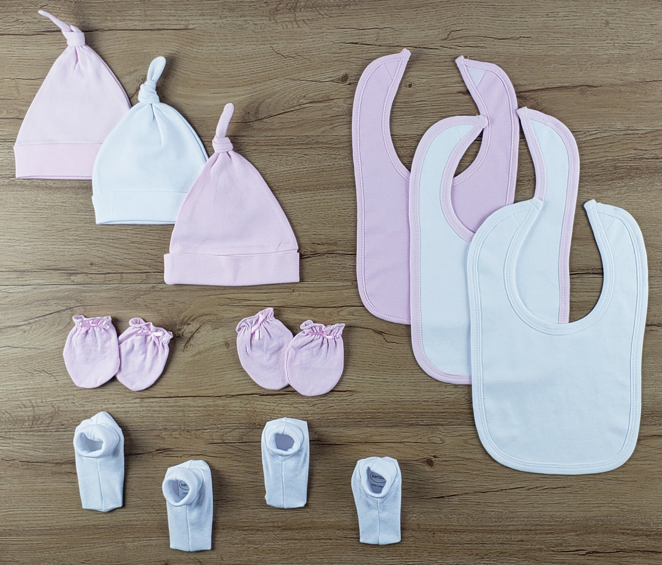 Bambini 10 PC set featuring soft cotton bibs, caps, and booties in pink and white, perfect for newborns.