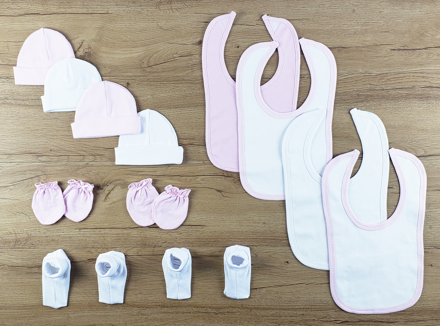 Bambini 12 PC set featuring soft cotton bibs, caps, and booties in pink and white, perfect for newborns.