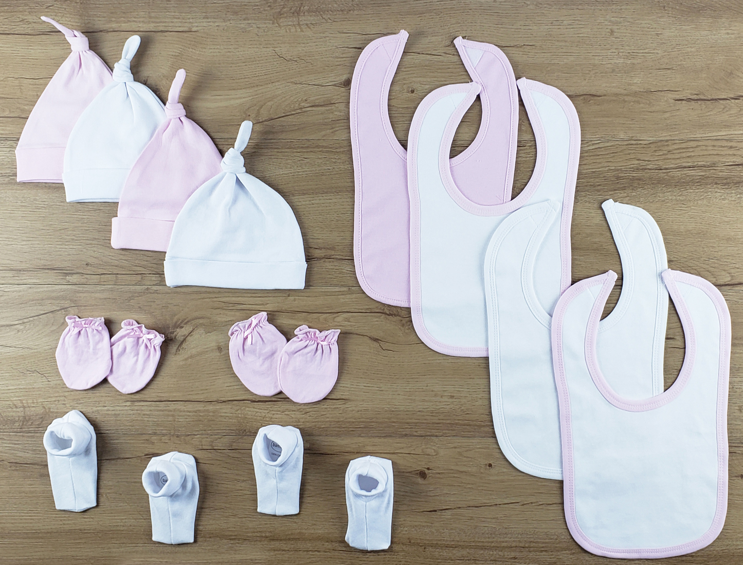 Bambini 12 PC set featuring soft cotton bibs, caps, and booties in pink and white, perfect for newborns.